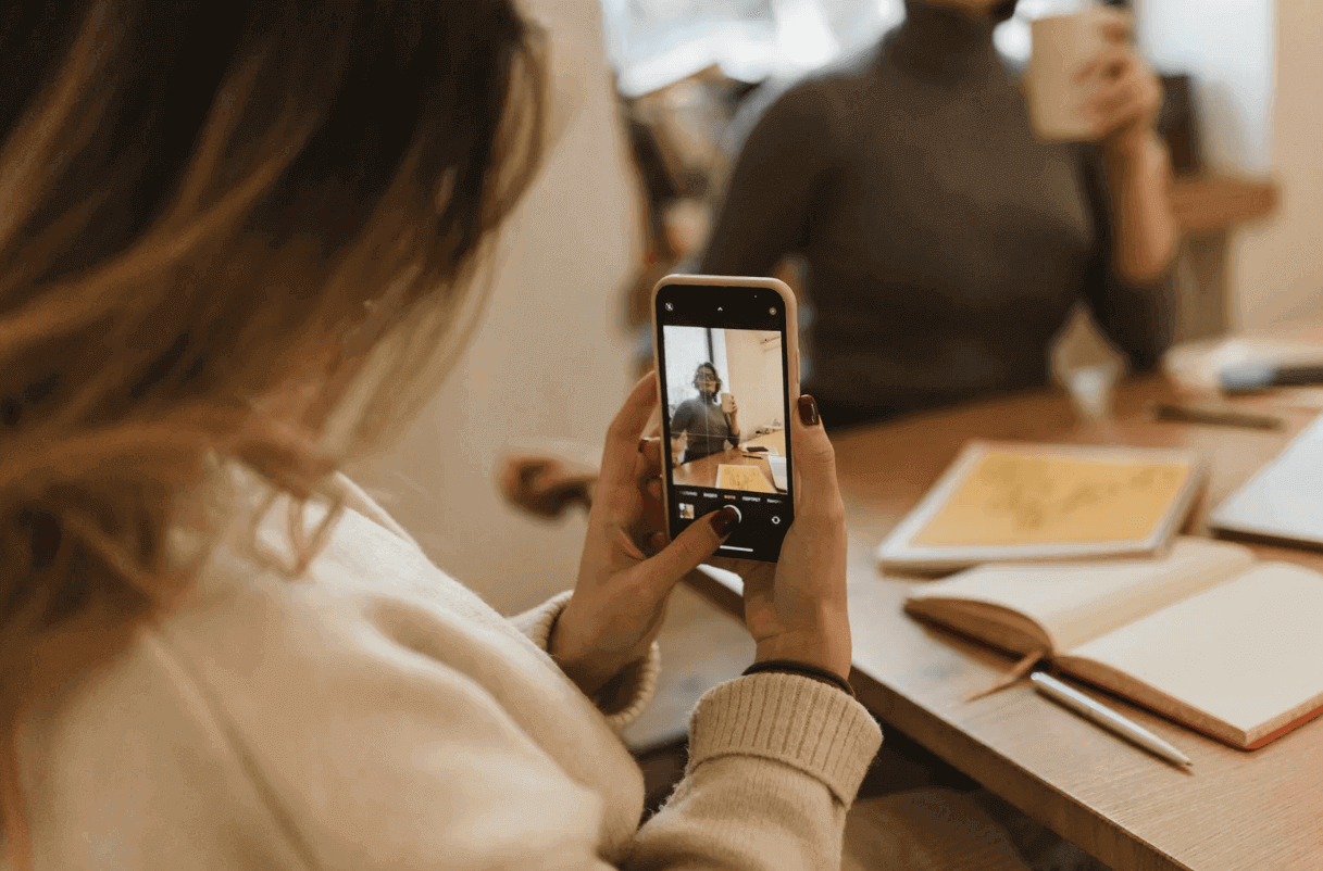 Femme prenant une photo avec un téléphone, présentant une coque iPhone transparente et tendance