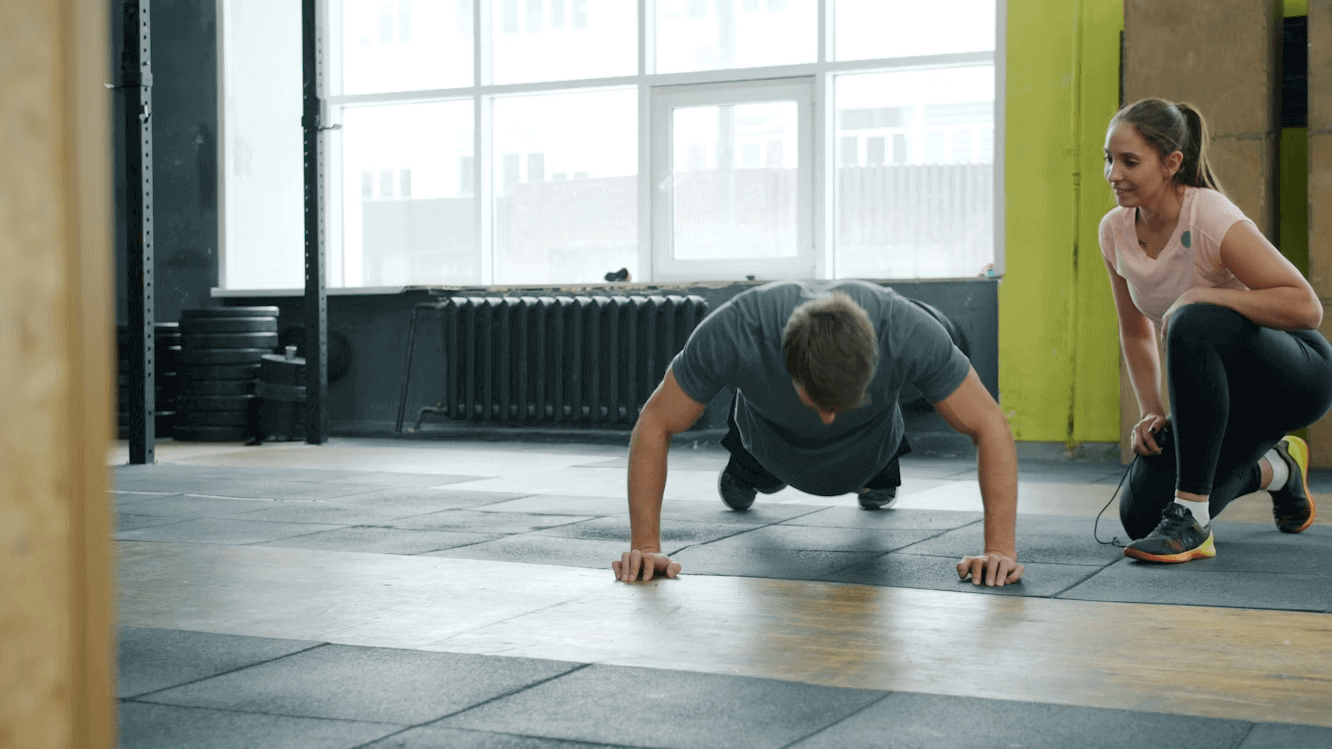 Homme et femme faisant des pompes dans une routine de remise en forme en salle de sport